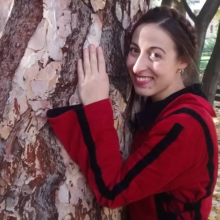 woman with a red jacket touching a tree